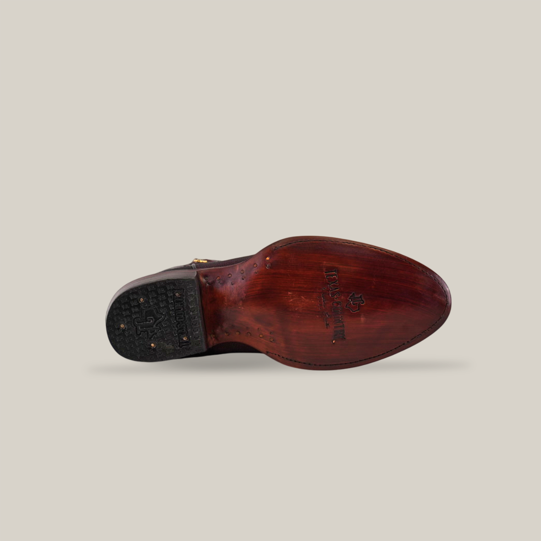 The image showcases the underside of an Exotic Stingray - Wine - Round Toe shoe, with a polished leather sole and visible nails. The black heel has textured grips, and the logo and text are elegantly stamped. A plain, light background enhances its luxurious appeal.