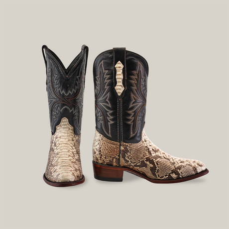 The Exotic Python - Natural - Round Toe boots are handcrafted with intricate detailing. They feature a mix of textures: an exotic python pattern in brown and beige on the lower part, and black upper with decorative stitching, set against a solid beige background.