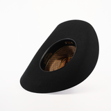 The 6X Doble SS Black showcases a wide-brimmed design, tilted to reveal an intricate interior with golden patterns. Set against a plain white background, it highlights the hats elegant shape and texture, echoing the timeless charm of Western headwear.