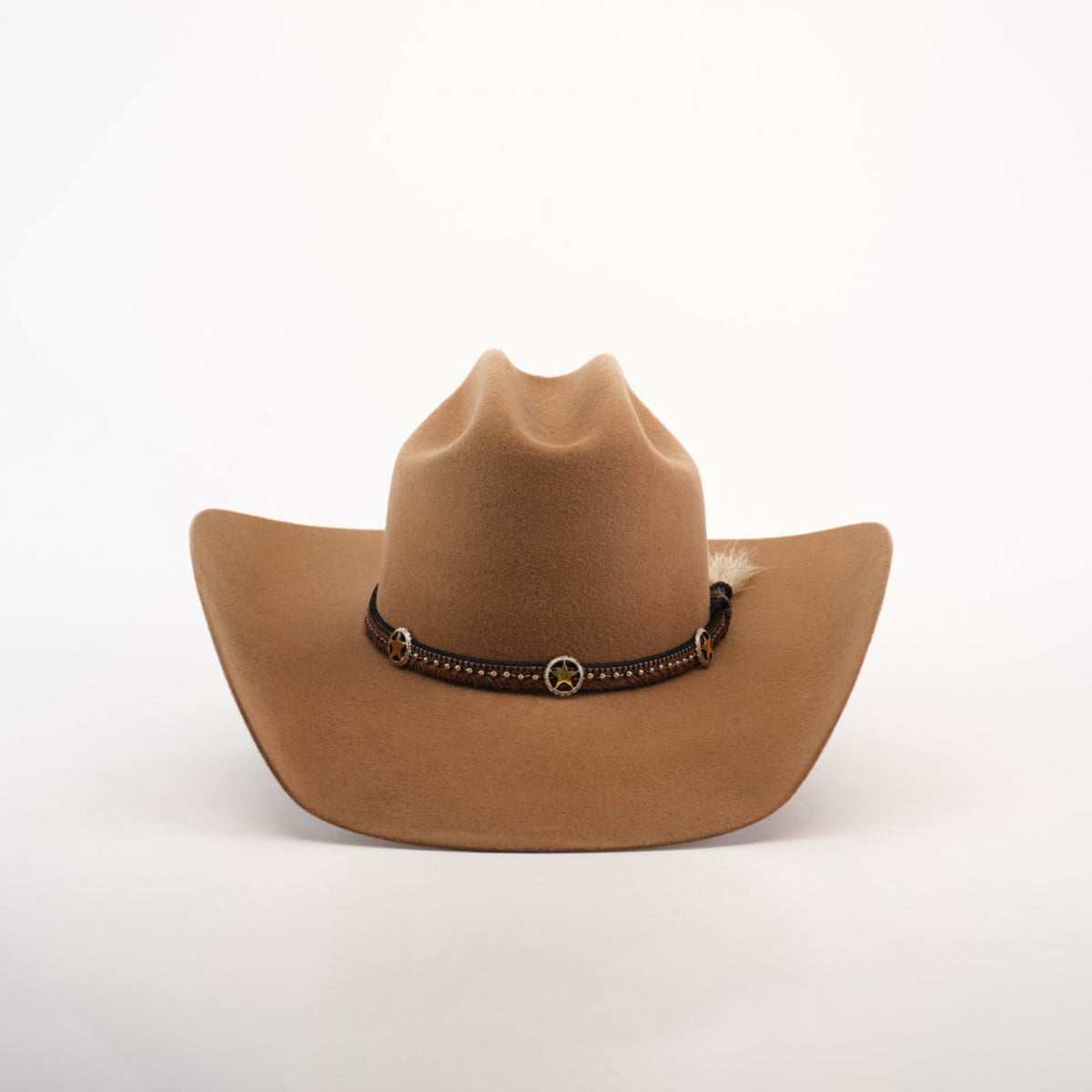 The 6X Doble SS Fawn is a brown felt cowboy hat with a dark leather band, decorative conchos, and a small feather on the side, displayed on a plain white background.