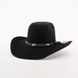 The 6X Brazil Black cowboy hat boasts a wide brim and is crafted from Brazil felt. It features a decorative braided band with silver accents and a small feather, capturing Western heritage against a plain white background.