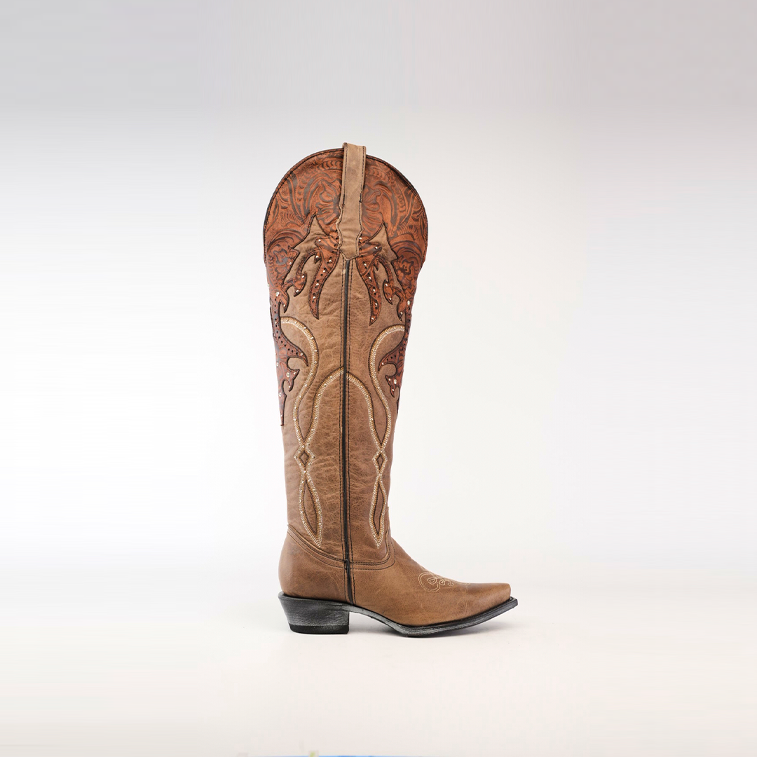 The Miriam Cappuccino Tall Shaft boot, with its intricate dark brown stitching and embroidery, features a handcrafted design with a pointed toe and low heel, elegantly displayed on a plain white background.