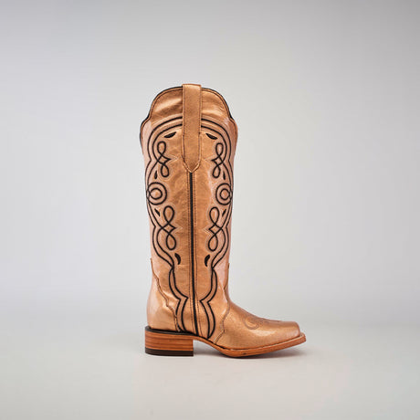 A single Eden Rose Gold cowboy boot with intricate black embroidery on a shiny surface, featuring a wooden heel and narrow square toe, set against a plain gray background.