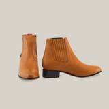 A pair of Grasso Honey Round Toe leather ankle boots with elastic side panels is set against a white background. One boot shows the front view, while the other is angled to highlight their luxury Western craftsmanship and smooth texture.