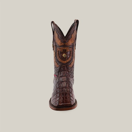 Front view of the Exotic American Alligator Hornback boot in brown, showcasing intricate craftsmanship with a textured pattern and decorative shield emblem. This square-toed boot features a tall shaft, set against a plain background.