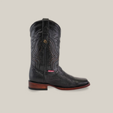 A single black Exotic Lizard - Black - Rodeo Toe cowboy boot, crafted with intricately carved lizard leather and a brown wooden sole, is showcased on a neutral background. It boasts detailed embroidery on the shaft and a small red and white label near the heel for added allure.