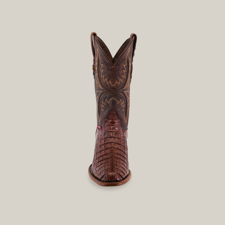 Front view highlighting a handcrafted brown Exotic Caiman Hornback cowboy boot, expertly made from genuine caiman leather with intricate stitching and textured shaft and foot. This round-toe design is set against a plain light background with a slightly worn sole.