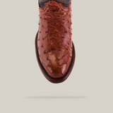 The Exotic Full Quilt Ostrich - Brandy - Round Toe cowboy boot, in brown ostrich leather, flaunts distinctive bumps and a central seam. It is displayed against a pale background with a subtle shadow beneath.