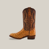 Side view of the Exotic Full Quilt Ostrich - Paja featuring a light brown ostrich leather lower and a darker brown upper with intricate stitching, showcasing its timeless Western heritage against a plain light gray background.