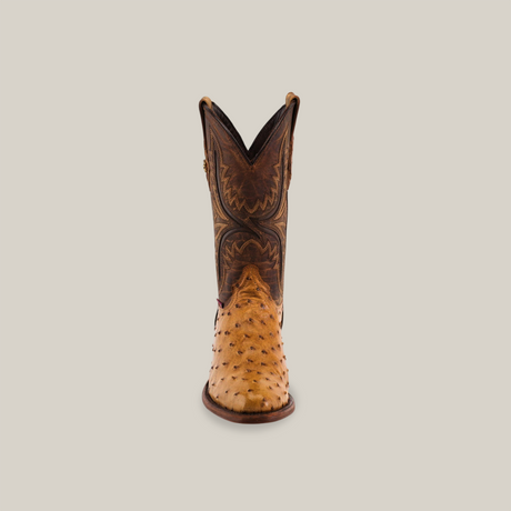 The Exotic Full Quilt Ostrich - Paja - Round Toe boot features intricate patterns with a brown and tan leather design and ostrich texture on the foot, all set against a simple light backdrop, embodying true Western heritage.