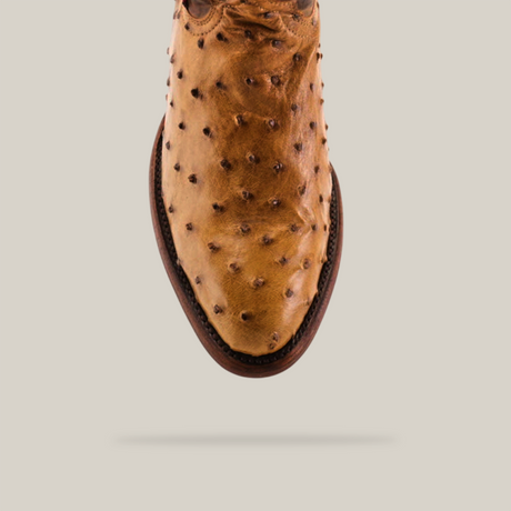 Close-up of the Exotic Full Quilt Ostrich - Paja - Round Toe shoe in brown ostrich leather, highlighting its texture and brown sole. Positioned vertically against a plain background, it showcases the Western Heritage design and elegant toe end.