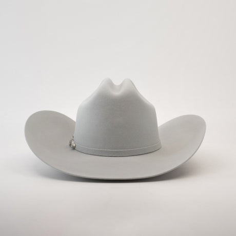 The 10X Jerarca Platinum, a light gray fur felt cowboy hat from the Larry Mahan collection, features a wide brim and a pin on the band, photographed against a plain white background.