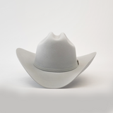 The 100X Independencia Platinum cowboy hat, in light gray, captures the El Presidente style with its wide brim and slightly curved crown, elegantly resting on a smooth surface.