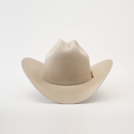 The 10X Jerarca Belly is a beige fur felt cowboy hat with a wide brim and creased crown, embodying classic western style, set against a plain white background.