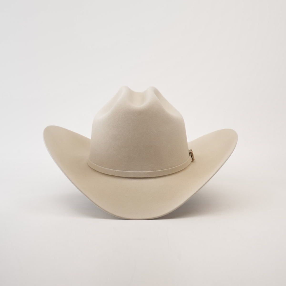 The 100X Independencia Belly, a beige cowboy hat made of premium full beaver fur, features a wide brim and a stylish crown crease, elegantly displayed on a plain white background.