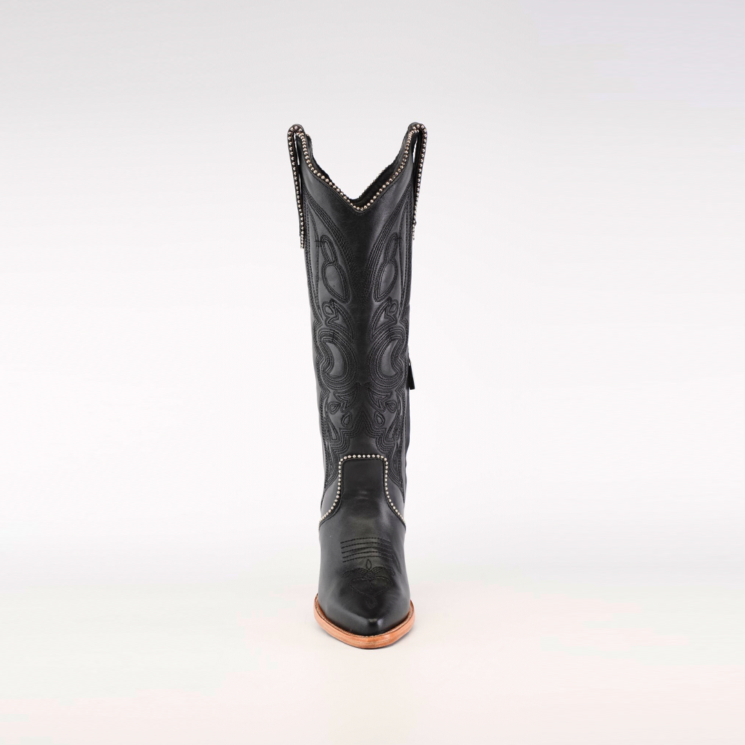 The Linda Studs Tall Shaft Black boot from the Platinum Collection is presented on a neutral background, showcasing intricate decorative stitching, a pointed J toe, and a wooden sole with elegant swirling patterns.