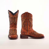 The Butterfly Studs Cogñac boots are crafted from cowhide leather with intricate butterfly embroidery and swirling patterns. They feature a square toe, classic Western style, pull tabs, and a low heel, all set against a plain white background.