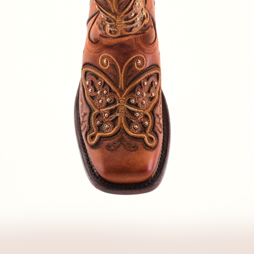 A top view of the Butterfly Studs Cogñac boot, featuring square toes and intricate butterfly embroidery on brown cowhide leather, displayed on a plain white background.