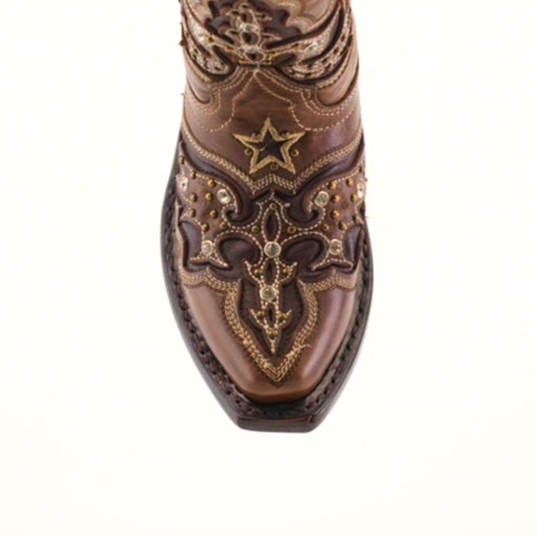 A close-up of the Chantal Crystals Camel - Snip Toe boot showcases ornate embroidery and decorative metal accents on premium cowhide leather. Expert artisanship is evident in the star and swirl patterns. The boot, viewed from above, rests against a plain background.