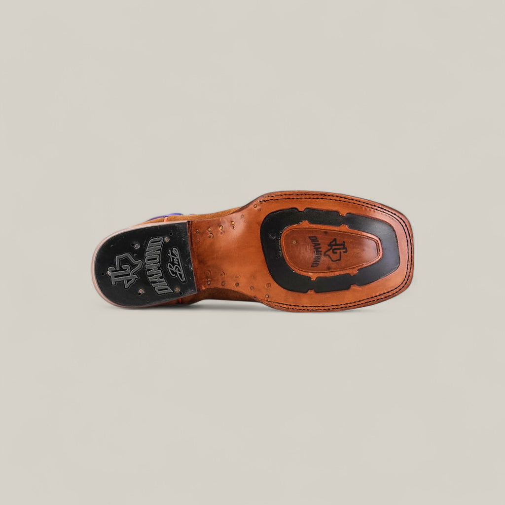 The Bronson - Gold - Square Toe mens boot showcases a brown leather underside with black rubber sole insert and branding, photographed on a light beige background—ideal for those who value quality square toe boots.