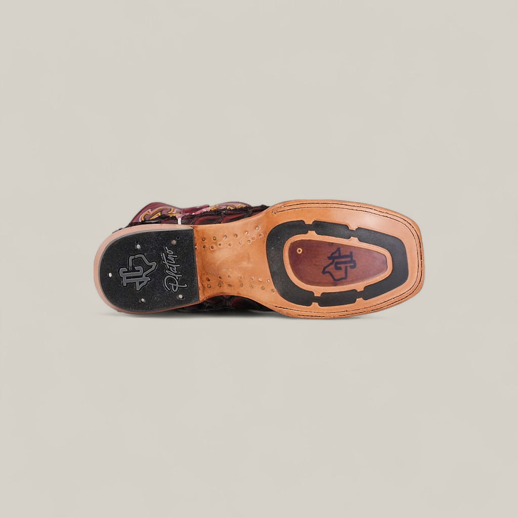 The image shows the sole of the Maverick - Wild Cherry - Square Toe dress shoe, featuring a mix of tan and black leather with stitched details, a metal anchor logo, signature near the heel, and a striking square toe design.