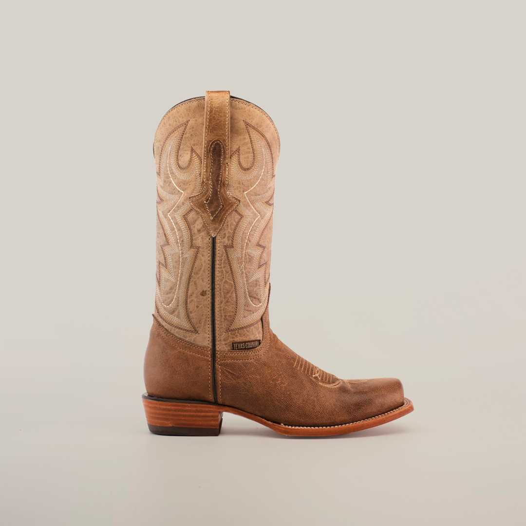 A single Sierra Fawn Wide Cutter Toe boot, made from premium tan cowhide leather with intricate stitching, is shown against a white background. It features a low wooden heel and pull straps, capturing authentic cowboy style.