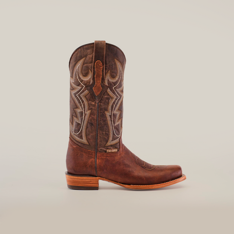 The Fresno Cogñac - Wide Cutter Toe cowboy boot, made from rich cowhide leather, features intricate stitching and a wooden heel. Its wide cutter toe and decorative shaft patterns embody the traditional Western style against a plain white background.