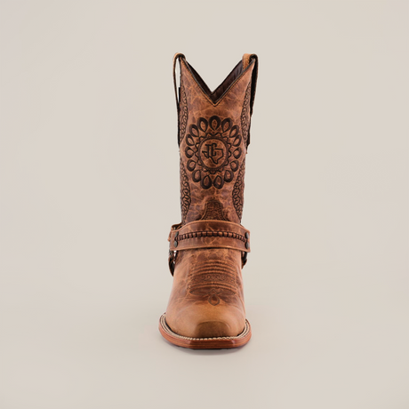 The Siberia Fawn - Biker Toe is a brown cowboy boot made from premium cowhide. It is displayed against a white background, showcasing intricate embossed patterns and decorative designs on the front, with mid-calf height and a sturdy, rounded toe.