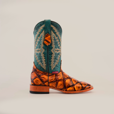 The Big Bass Pirarucu Print Tan - Square Toe is a handcrafted cowboy boot featuring a textured cowhide leather foot with detailed patterns, a tall teal shaft with intricate embroidery, a flat heel, and a smooth sole.