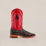 The Big Bass Pirarucu Print Rustic Black - Square Toe boot, made from premium cowhide leather, showcases a textured black lower section and a vibrant red upper shaft with intricate embroidery. It features a wooden heel and is elegantly displayed against a plain white background.