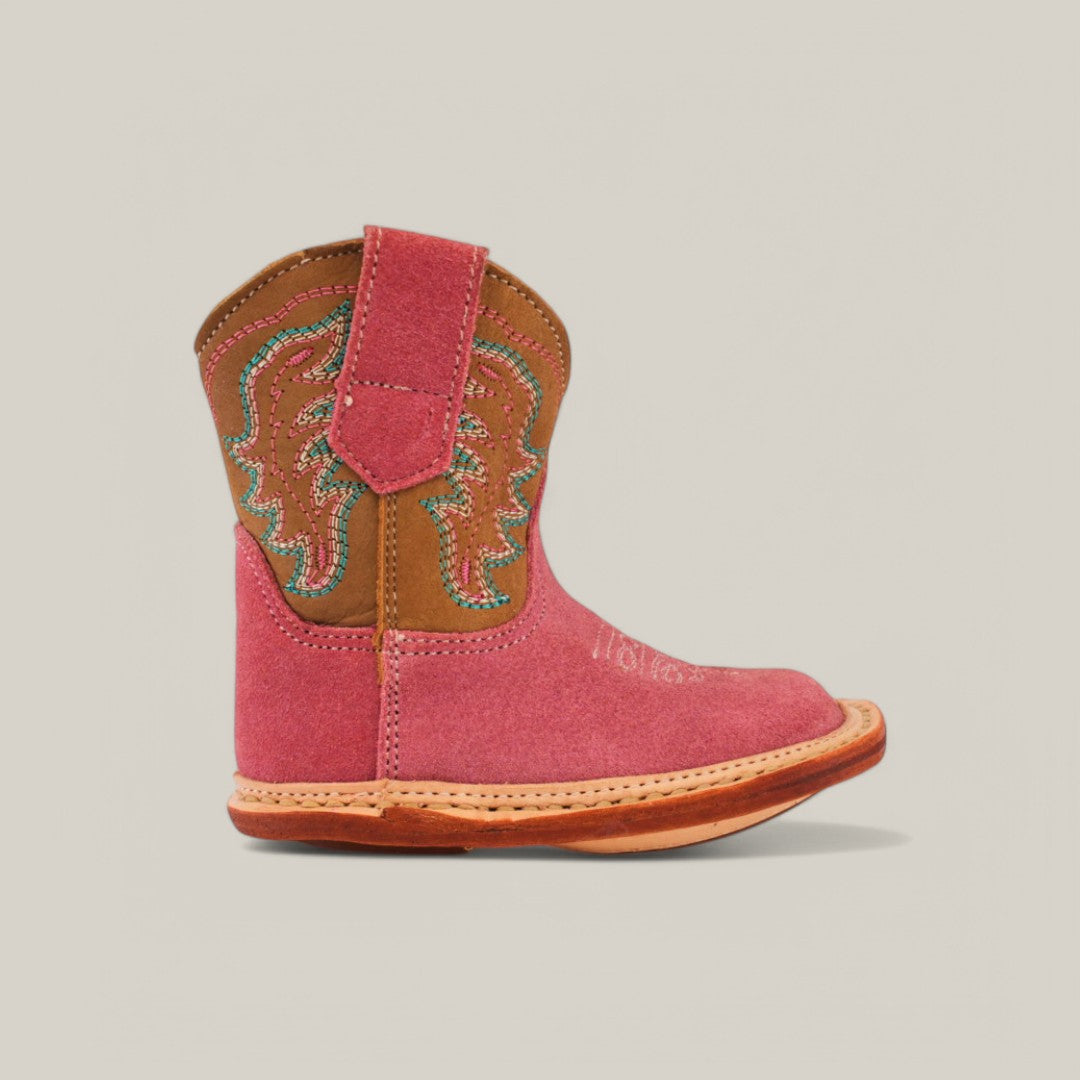 The Harper boot features adorable pink suede with a camel shaft, square toe design, brown leather accents, and colorful stitched patterns. It has a thick tan sole, making it charming and stylish for your little one.