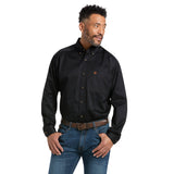 A man in a Solid Twill Classic Fit Shirt Black - 10000502, featuring embroidered chest pocket details, pairs it with blue jeans and a brown belt. Hands in pockets, he looks to his left.