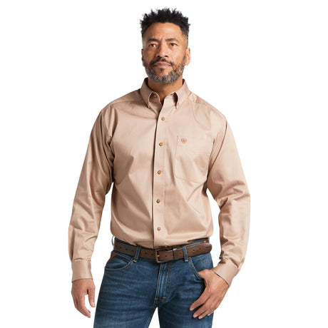 A man with short curly hair and a beard wears the Solid Twill Classic Fit Shirt Kaki - 10000505, featuring elegant embroidery. Paired with a brown belt and jeans, he stands against a plain white backdrop, exuding timeless style.