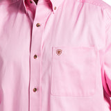 The Solid Twill Classic Fit Shirt Pink (10016692) offers a close-up view of its classic design, featuring an embroidered logo on the left chest pocket, brown buttons, and a buttoned collar. Its light pink hue makes it versatile for any occasion.