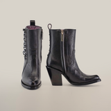 On display from the Platinum Collection are two black Francia Rings Bootie Black - J Toe leather ankle boots. The left showcases chain detailing, and the right has a zipper with a chunky heel. Handcrafted with a slight sheen and purple interior lining, they exude luxury at every step.