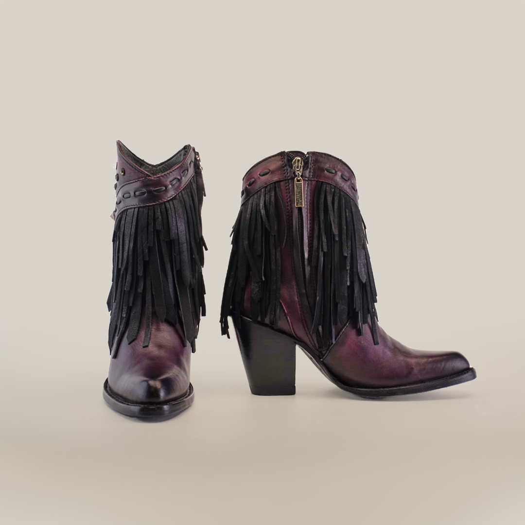 Introducing the Austin Fringe Bootie Wine - J Toe: premium leather ankle boots in dark mauve, showcasing black fringe details, decorative studs, and chunky high heels with side zippers, all set against a plain white background.