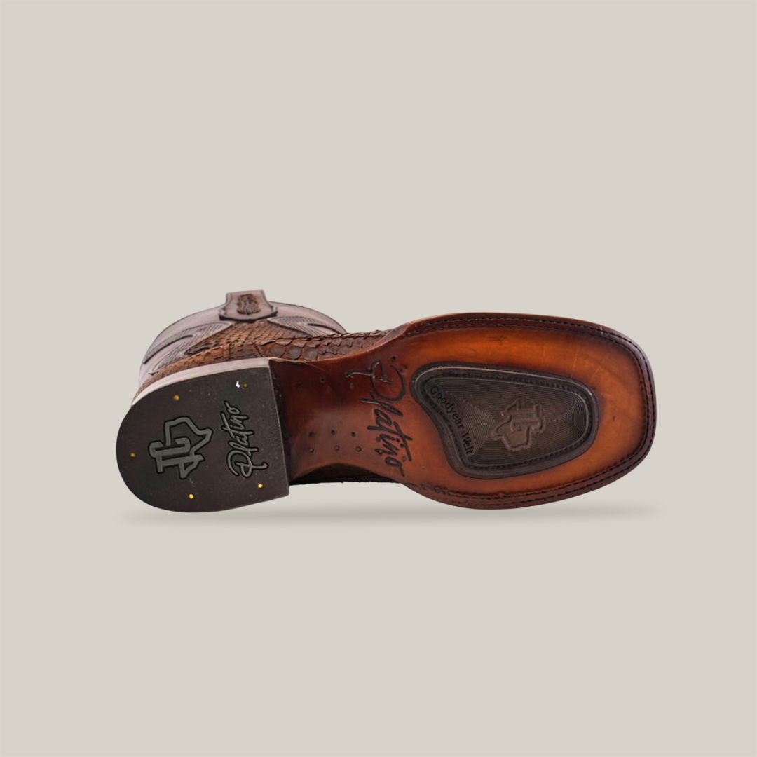 The image displays the sole of the Exotic Python - Diamond - Tamarindo Square Toe cowboy boot, featuring intricate patterns and branding. The heel and sole are dark brown with a visible logo near the middle, all positioned sole facing up.