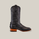 The Exotic Caiman Tail - Diamond - Black - Square Toe boot showcases a textured alligator pattern, intricate stitching, and a brown wooden heel. Side-profiled against a light gray backdrop, these Platinum Collection boots radiate elegance and style.