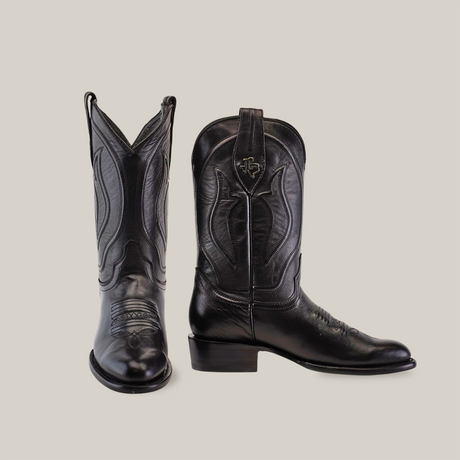 A pair of black cowboy boots from the Western - Platinum - Black - Roper Toe collection is displayed on a plain white background, with the left boot shown front-facing and the right boot side-facing, highlighting intricate stitching, roper toe, and stacked heel.