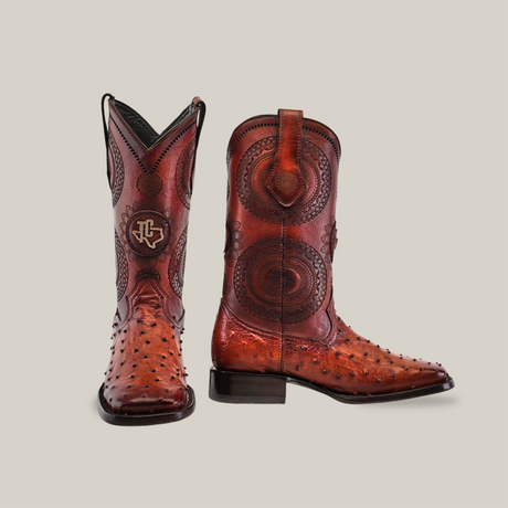 Two Exotic Karoo Ostrich boots in honey, featuring a square toe design from the Platinum collection. The left boot stands upright while the right shows off its intricate patterns and detailed craftsmanship—a genuine piece of cowboy culture.