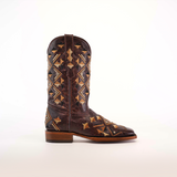 Against a white backdrop stands a single Maya Brown Short Shaft boot, featuring intricate tan and brown geometric patterns. This wearable art is crafted from premium leather with a low heel and a square toe.