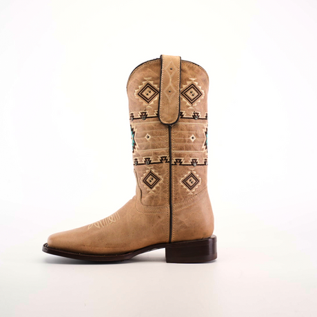 The Palles Aztec Stitch Fawn boot features a tan color, Aztec-inspired brown and teal geometric stitching on the shaft, a square toe, and a dark heel, set against a plain white background.