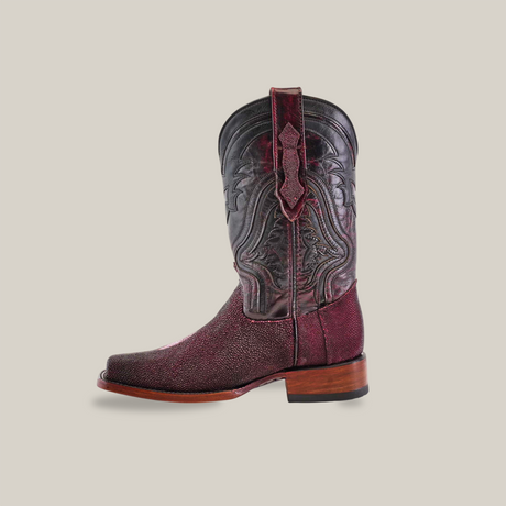 A single Exotic Stingray - Wine cowboy boot, crafted from luxurious stingray leather with intricate black stitching and a wooden heel, set against a plain beige background.