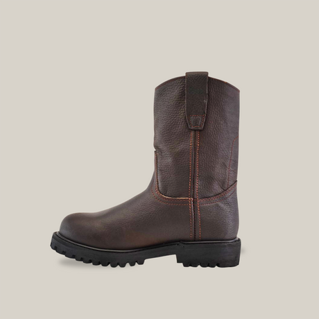 The Brown Roper - Tractor Sole - Composite Toe features premium dark brown cowhide leather, a thick black tractor sole, orange stitching, and a pull-on tab. Displayed sideways against a plain white background, the boot showcases its artisanal quality and left profile.