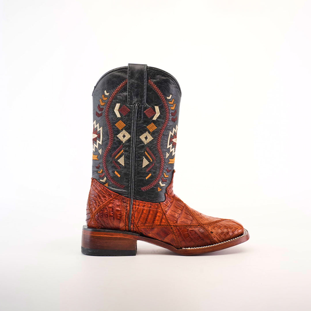 The Exotic American Alligator Patchwork Cogñac Square Toe boot features a black upper with colorful, geometric embroidery resembling a patchwork design. The lower part is made of textured brown alligator leather with a slight heel, set against a plain white background.