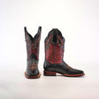 A pair of Grecas Black boots with ornate handcrafted black and burgundy leather, intricate floral embroidery, and decorative stitching. One boot stands upright to highlight the square toe design; the other is tilted to display the craftsmanship.