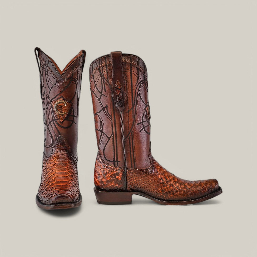 The Over Brown Python Laser & Embroidery boots (CU401) feature a narrow square toe and intricate stitching with laser-engraved patterns on the shaft and foot. Displayed against a light grey background, one boot stands upright while the other is angled.