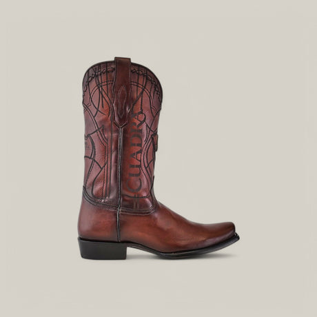 Brown Cuadra leather cowboy boot with intricate stitching, decorative shaft patterns, and CHARRO embossed on the side. The narrow square toe and black heel perfect this Over Chestnut Laser & Embroidery design against a light grey background.