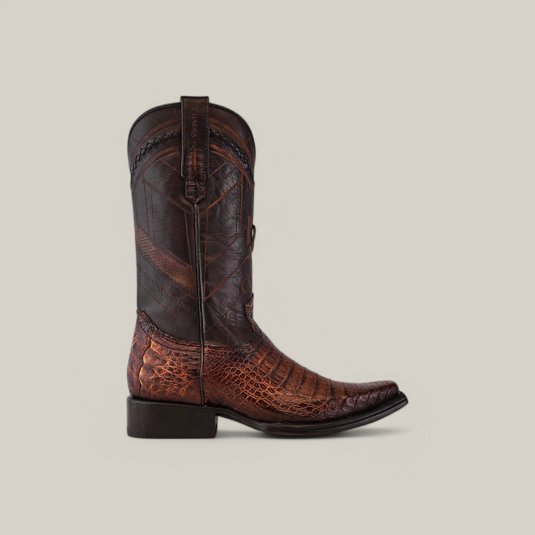 The Arauco Chocolate Caiman Laser & Woven - Narrow Square Toe - CU551 features a side view of a brown cowboy boot with a textured alligator-patterned lower section made from Caiman leather, a smooth darker upper section with laser-etched designs and intricate stitching, and a low heel against a plain background.