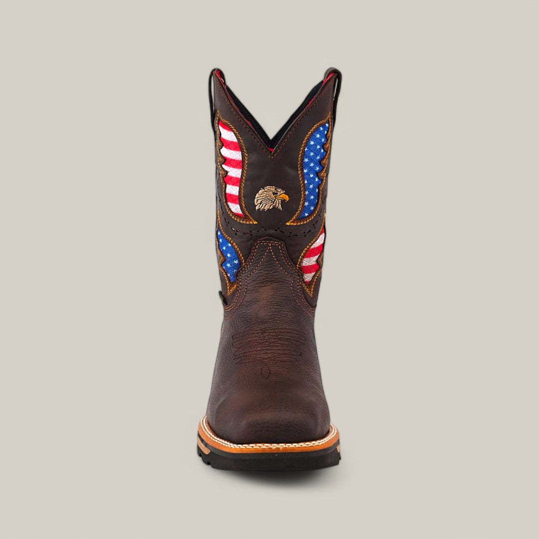 Front view of the Taurus Moka Soft Toe - E6189, featuring brown leather with American flag motifs and an embroidered eagle on the shaft. It is durable with decorative stitching and a light brown sole, set against a plain beige background.